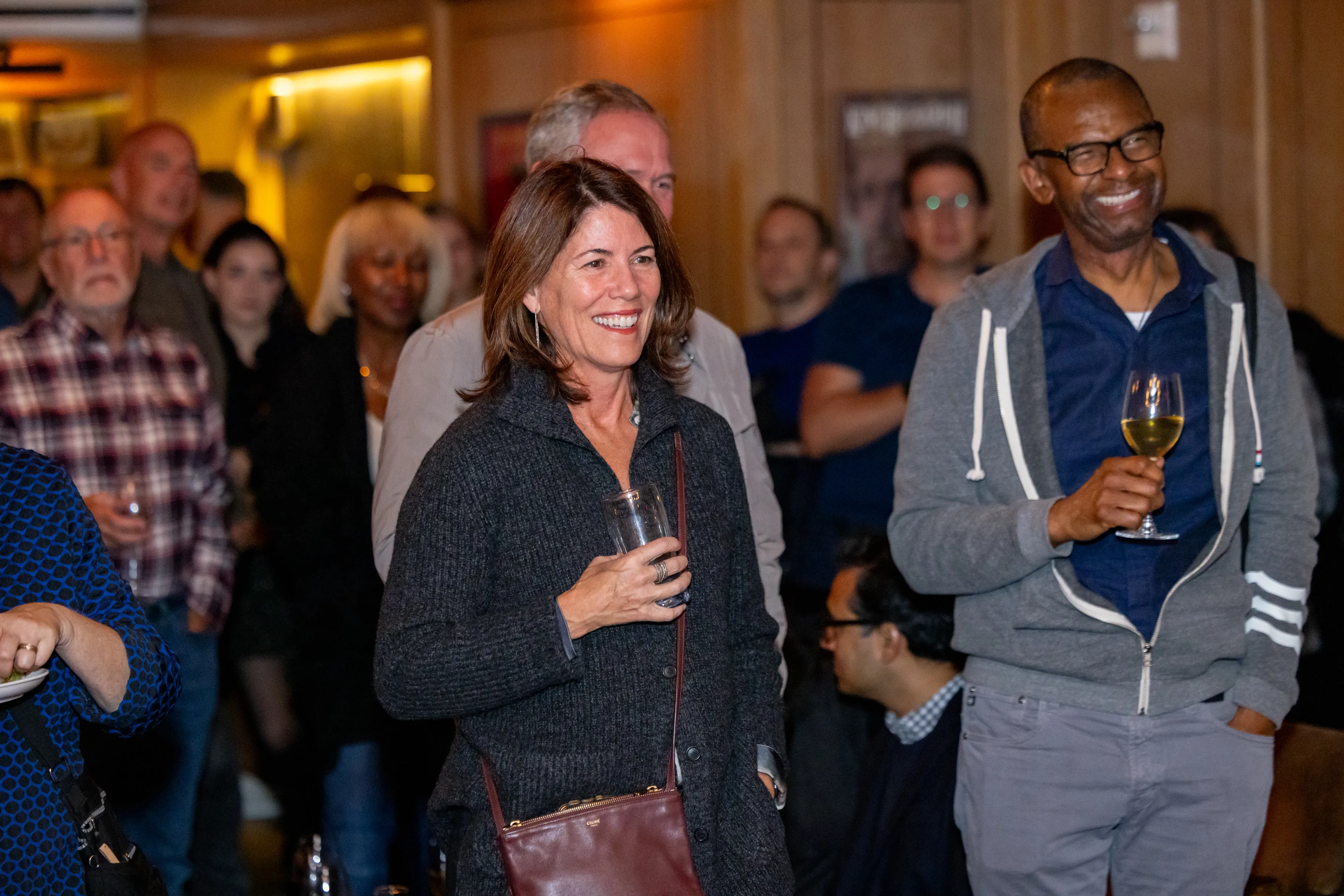 Two Partner members standing in a group at a Partner Evening cocktail reception in the The Library restaurant.