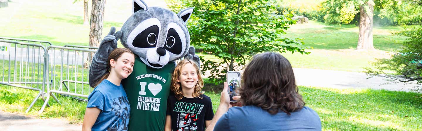 Visitors to The Delacorte Theater posing with Romeo the Raccoon mascot